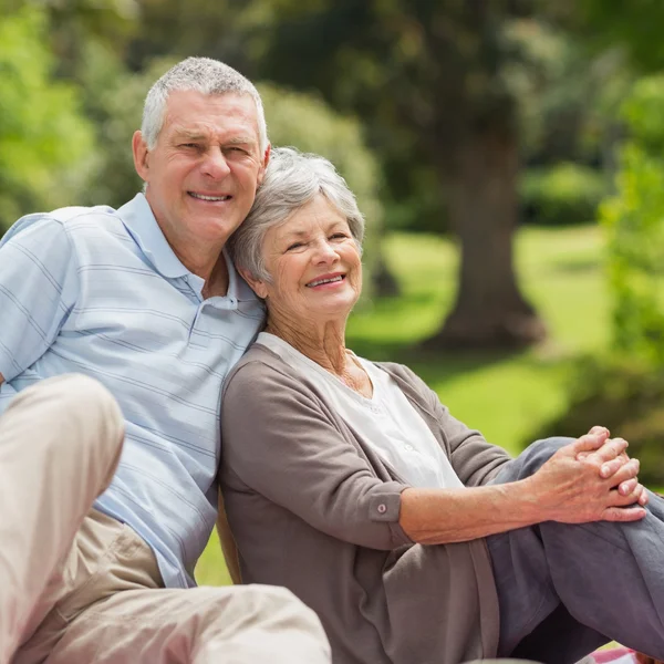 Sorridente coppia anziana seduta al parco — Foto Stock