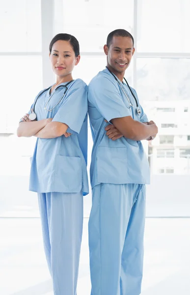 Confident surgeons standing back to back in hospital — Stock Photo, Image