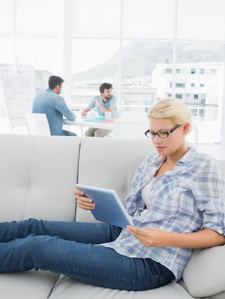 Vrouw met behulp van digitale tablet met collega's op achtergrond op crea — Stockfoto