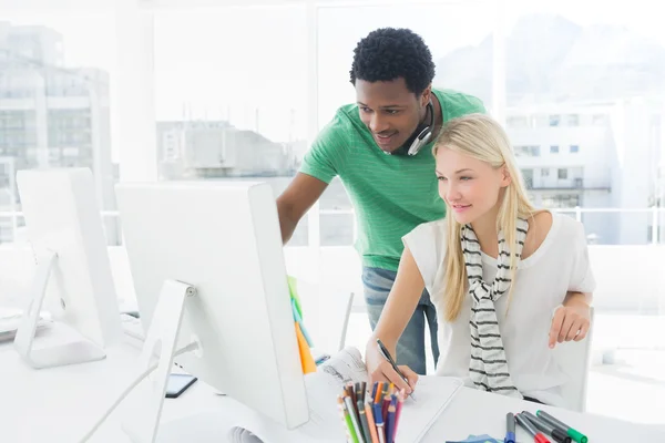 Kunstenaar tekenen iets op papier met collega op kantoor — Stockfoto