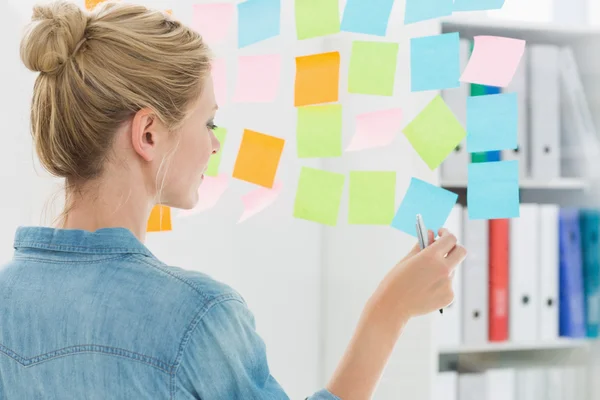 Vista trasera de una artista femenina mirando coloridas notas adhesivas — Foto de Stock