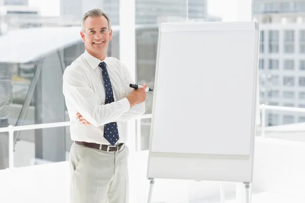 Smiling businessman standing at whiteboard with marker — Stock Photo, Image