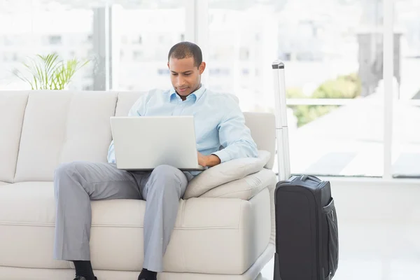 Uomo d'affari che utilizza il computer portatile in attesa di partire per un viaggio di lavoro — Foto Stock