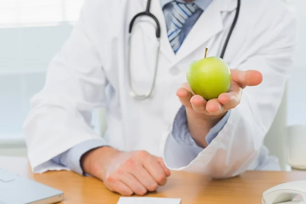 Середина чоловіка-лікаря, який тримає яблуко — стокове фото