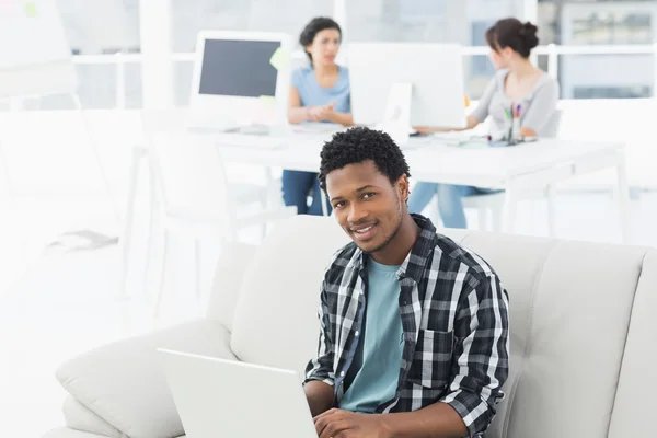 Man met laptop met collega's bij creatieve kantoor — Stockfoto
