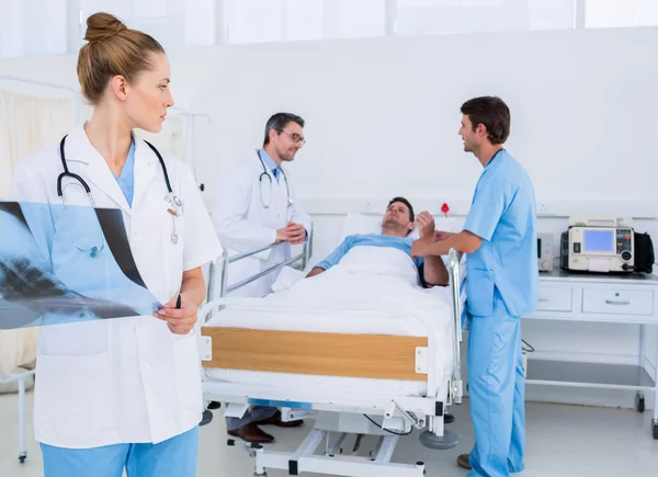 Doctor holding x-ray with colleagues and patient in hospital — Stock Photo, Image
