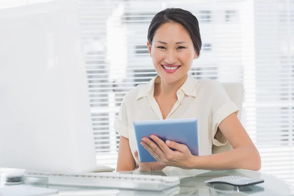 Smiling businesswoman using digital tablet at desk Stock Picture
