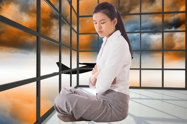 Composite image of businesswoman sitting cross legged with arms — Stock Photo, Image