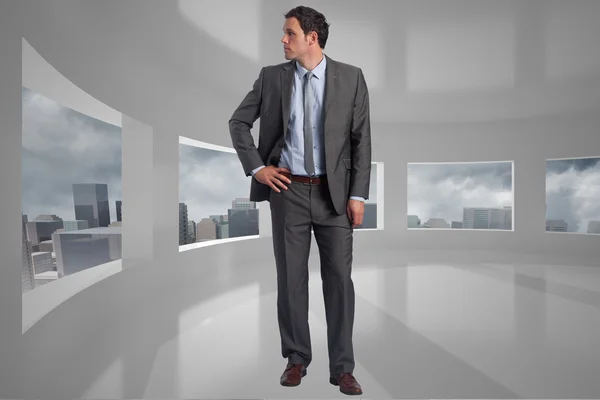 Composite image of serious businessman with hands on hips — Stock Photo, Image