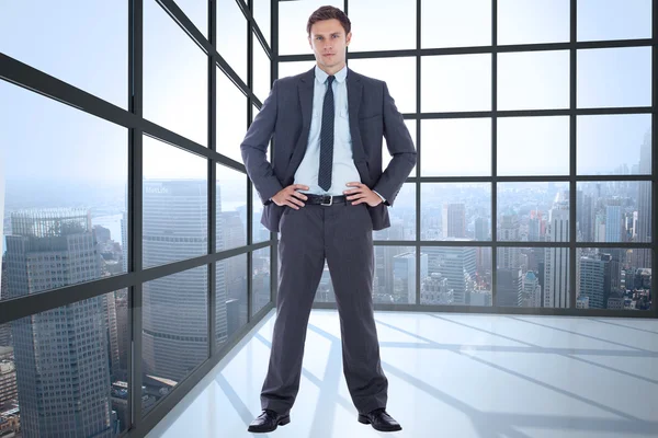 Composite image of serious businessman with hands on hips — Stock Photo, Image