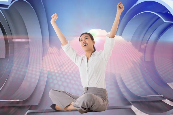 Composite image of businesswoman sitting cross legged cheering — Stock Photo, Image