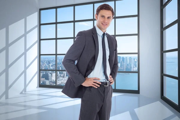 Composite image of smiling businessman with hands on hips — Stock Photo, Image