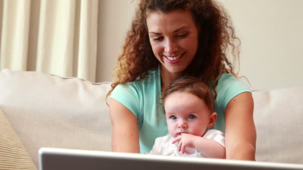 Mère utilisant un ordinateur portable avec bébé fils sur ses genoux — Video