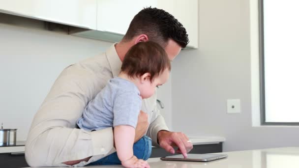 Padre che tiene in braccio il bambino prima del lavoro e usa tablet — Video Stock