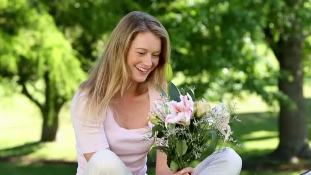 Girl smelling bouquet of flowers in the park — Stock Video