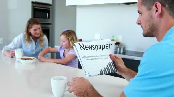 Pappa läser tidningen medan familjen har frukost — Stockvideo