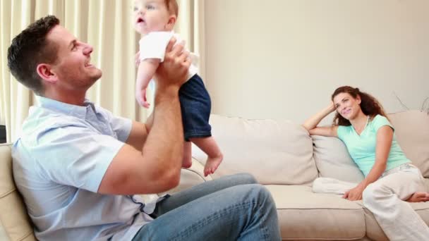 Mère regardant son partenaire jouer avec leur bébé sur le canapé — Video