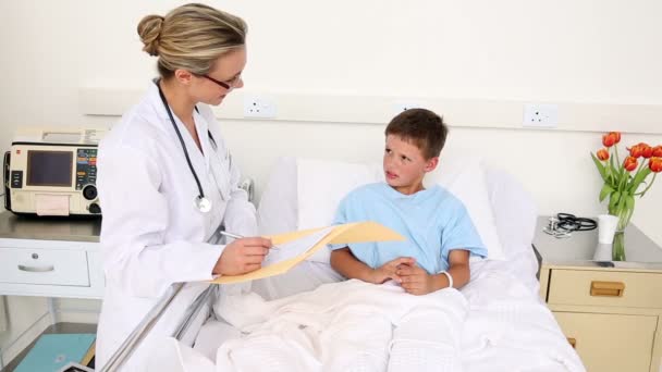 Pequeño niño enfermo sentado en la cama hablando con el médico — Vídeos de Stock