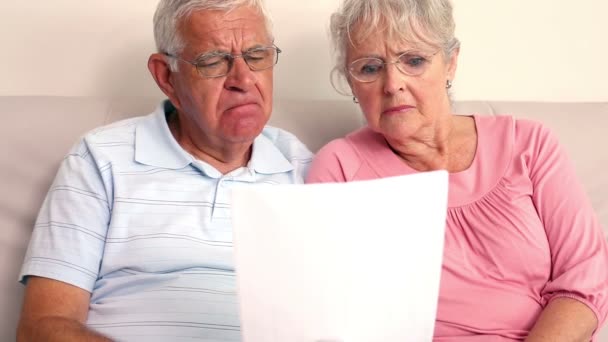 Беспокойная пожилая пара читает документ — стоковое видео