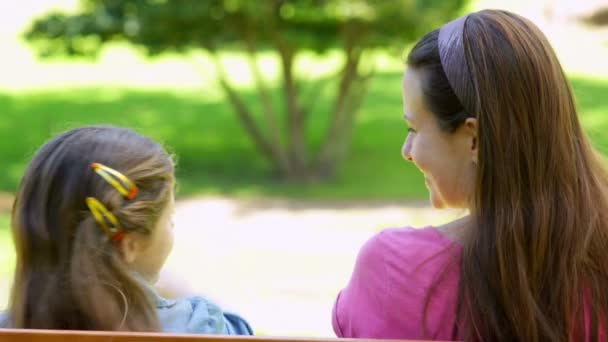 Madre e hija sentadas juntas en un banco del parque — Vídeo de stock