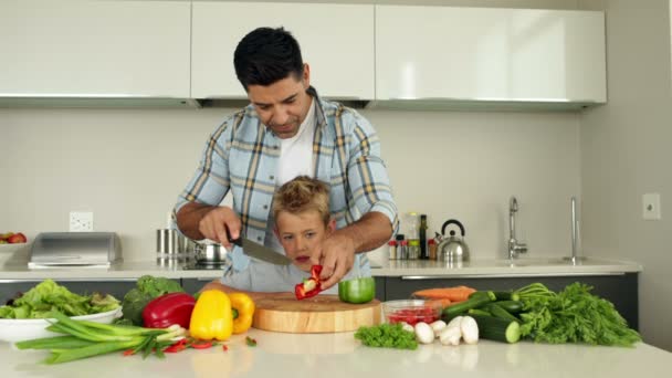 Vater bringt seinem Sohn bei, wie man Gemüse hackt — Stockvideo