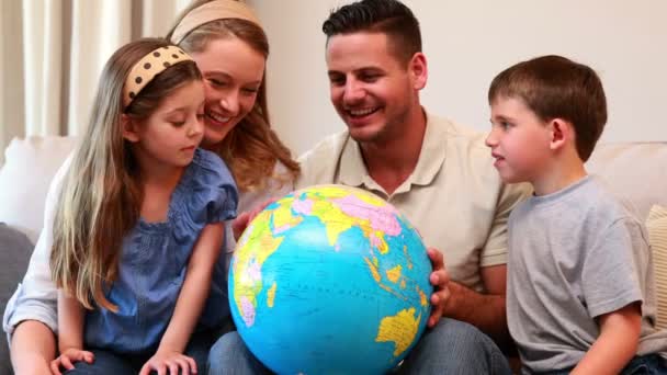 Jeune famille assise sur un canapé regardant le globe — Video