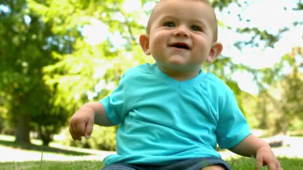 Niedliches Baby sitzt auf dem Gras — Stockvideo