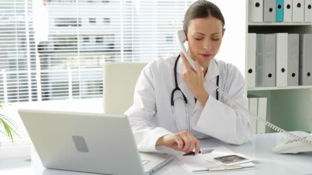 Doctor talking on the phone at her desk — Stock Video