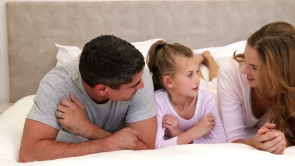 Parents et fille couchés sur le lit bavardage — Video