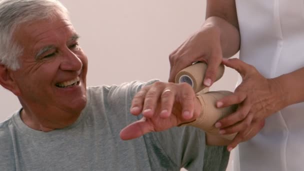 Фізіотерапевт перев'язування літнього чоловіка руки — стокове відео