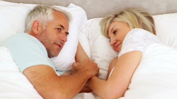 Happy couple chatting and holding hands in bed — Stock Video