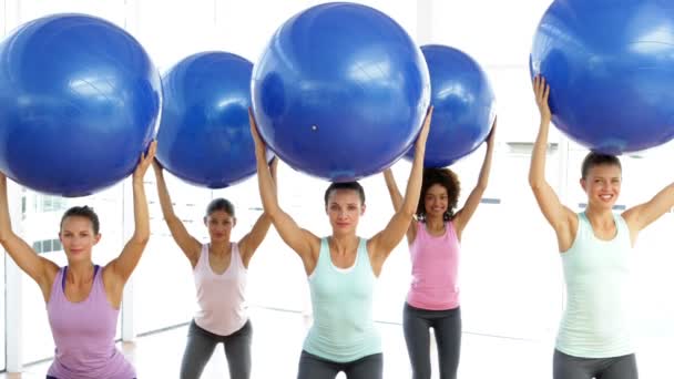 Cours de fitness en studio de levage de balles d'exercice tout en squattant — Video