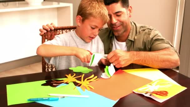 Vader en zoon maken papier vormen samen aan de tafel — Stockvideo