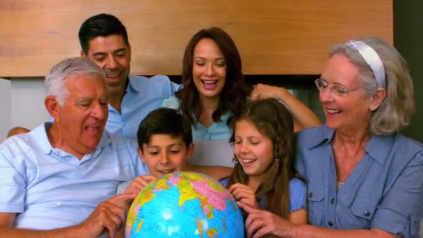 Extended family looking at globe together on couch — Stock Video