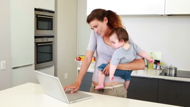 Mãe segurando seu menino feliz e falando no telefone usando laptop — Vídeo de Stock