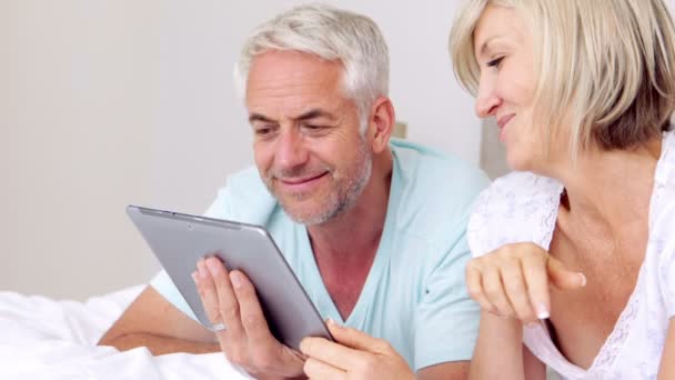 Happy couple lying on bed using tablet together — Stock Video