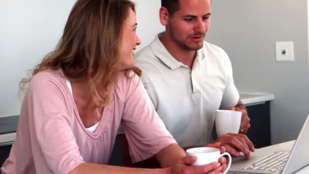 Пара пьет кофе и пользуется ноутбуком на кухне — стоковое видео