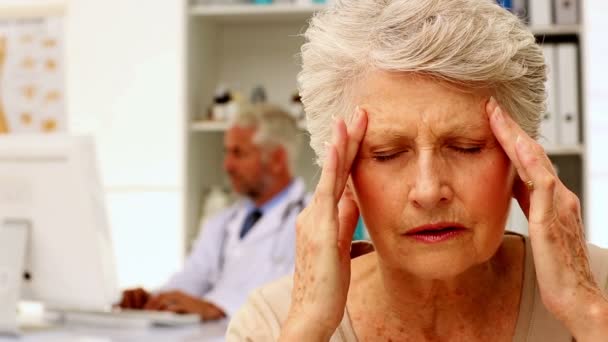 Seniorin mit starken Kopfschmerzen beim Arztbesuch — Stockvideo