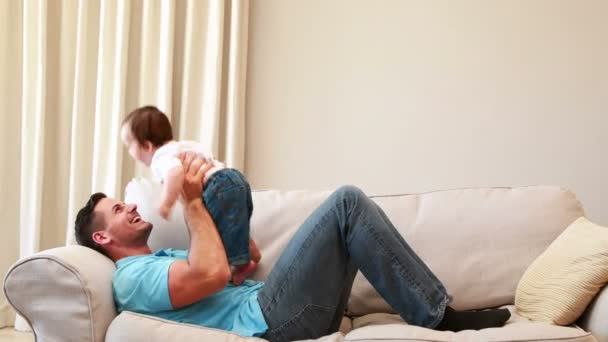 Padre jugando con su bebé en el sofá — Vídeos de Stock