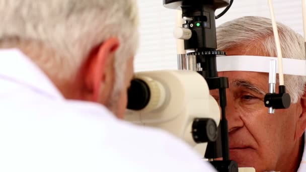 Médecin examinant les yeux du patient âgé — Video