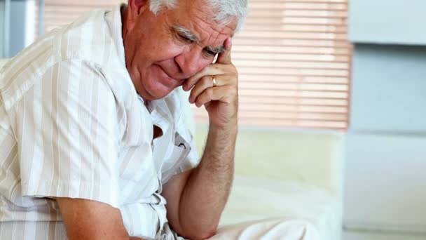 Депрессивный старший мужчина сидит на диване — стоковое видео