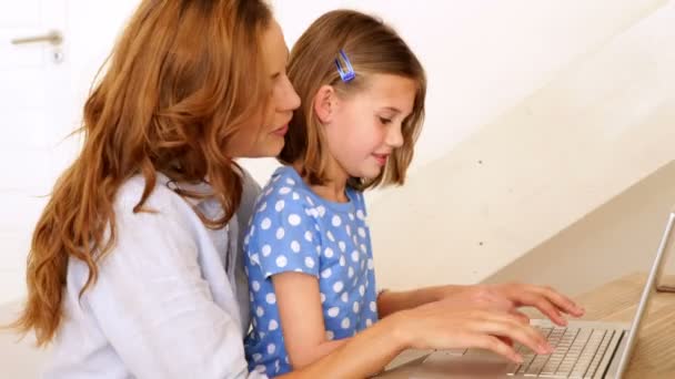 Little girl using laptop with her mother at the table — Stock Video