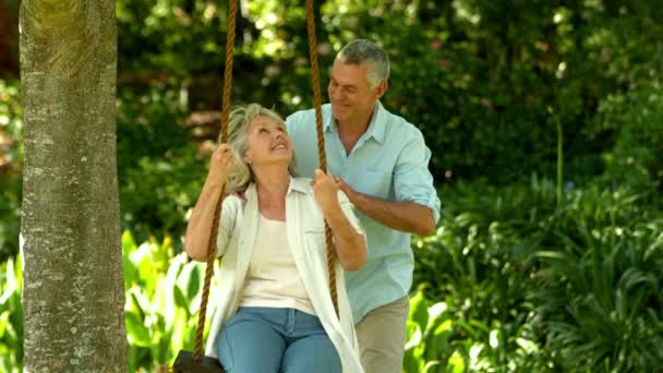 Senior homme pousser sa femme sur une balançoire — Video