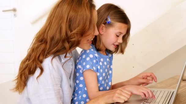 Menina usando laptop com sua mãe bonita na mesa — Vídeo de Stock