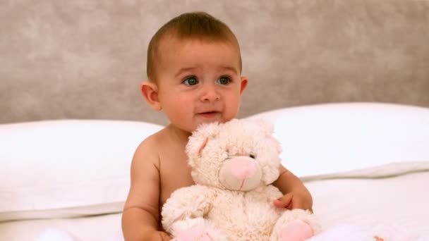 Lindo bebé en una cama con oso de peluche — Vídeos de Stock