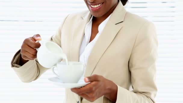 Mujer de negocios vertiendo leche en su taza — Vídeos de Stock