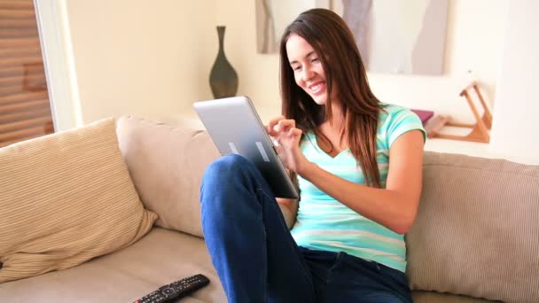 Mooie brunette ontspannen op de sofa met behulp van haar tablet-pc — Stockvideo