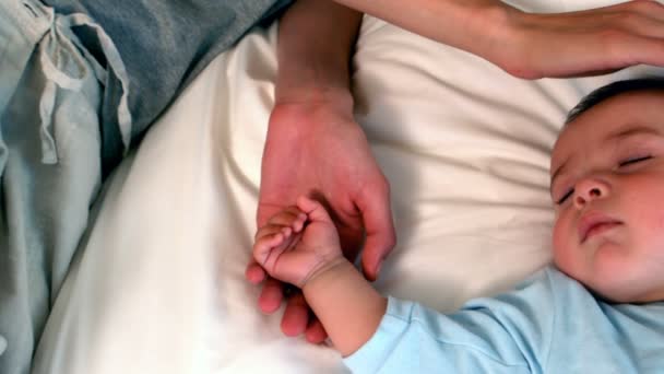 Mother lying with sleeping baby boy on bed — Stock Video