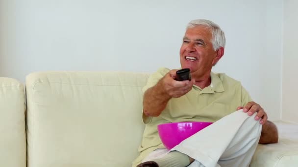 Seniorpaar sitzt auf Sofa vor dem Fernseher — Stockvideo