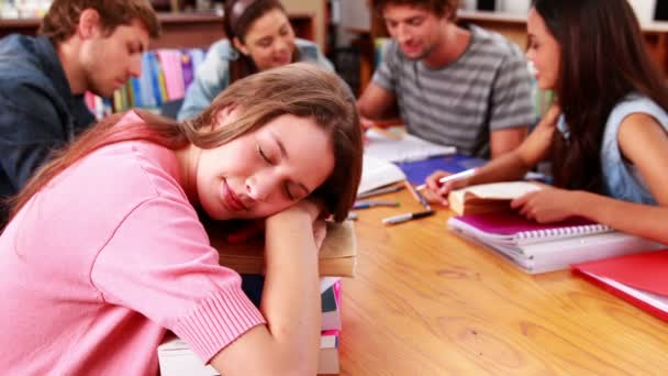 Estudantes estudando juntos na biblioteca com menina dormindo em livros — Vídeo de Stock